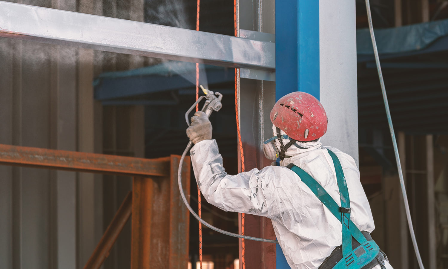 Worker paints a metal frame at construction site